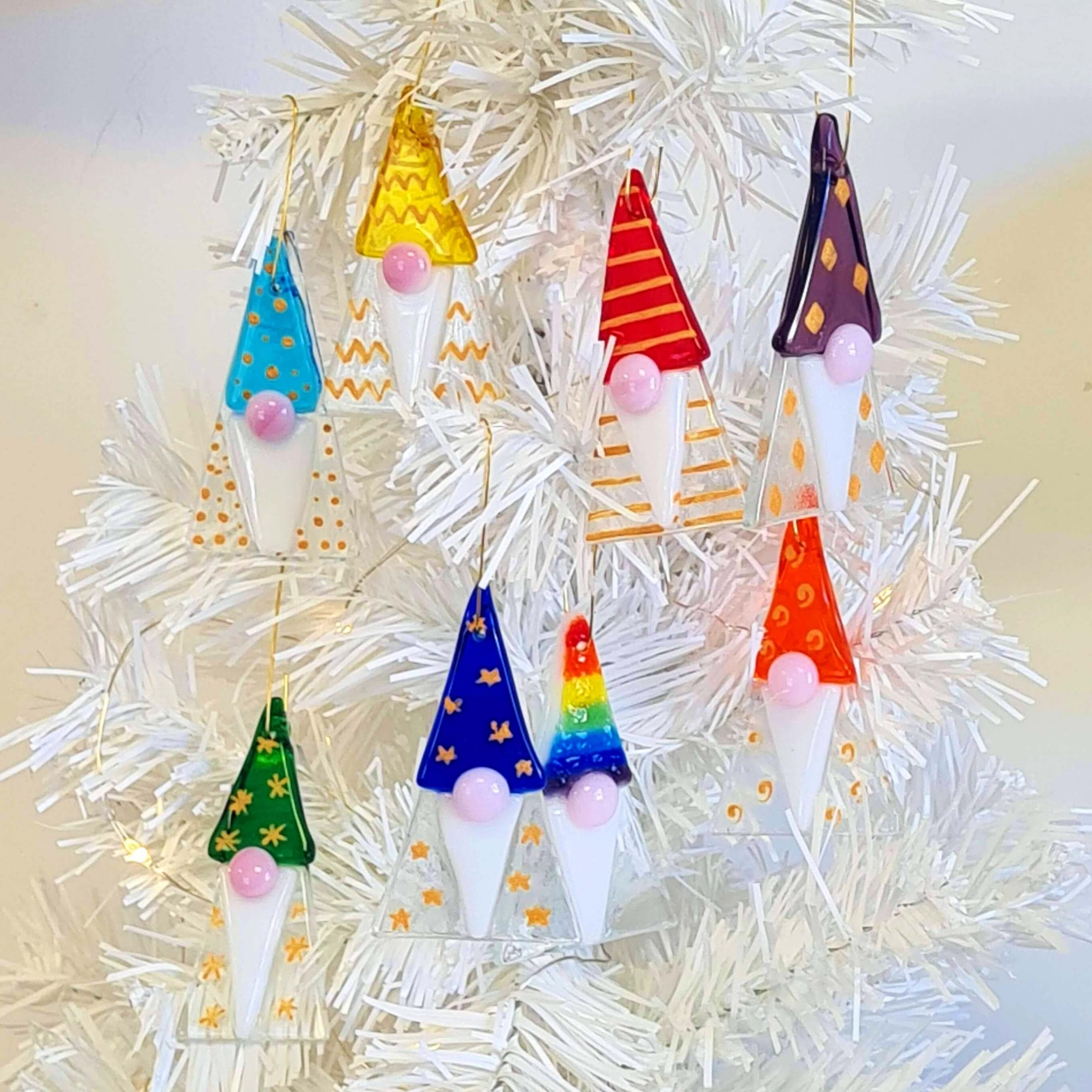 7 different coloured handmade fused glass christmas gonks on a white tree