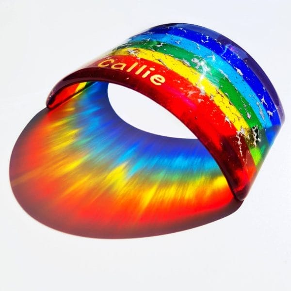 A Personalised Rainbow Bridge with cremation ashes fused insode the glass, on a white background.