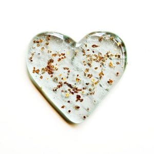Pet Cremation Ashes fused inside a clear heart with a sprinkling of gold glitter, on a white background.