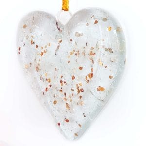 Cremation Ashes fused inside a clear hanging heart with a sprinkling of gold glitter, on a white background.