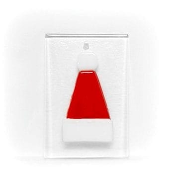 A red and white santa hat hanging ornament on a clear glass base