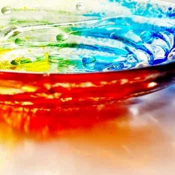 A close up of a handmade glass bowl showing red, orange,, green and yellow colours.