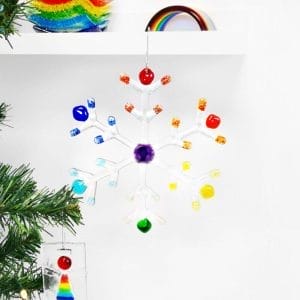 A large clear and Rainbow snowflake hanging from a shelf with a white background.