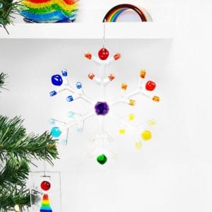 A large clear and Rainbow snowflake hanging from a shelf with a white background.