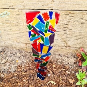 A rainbow glass plant stake in a flowerbed