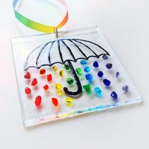 A Hanging suncatcher featuring a black umbrella with rainbow coloured raindrops.